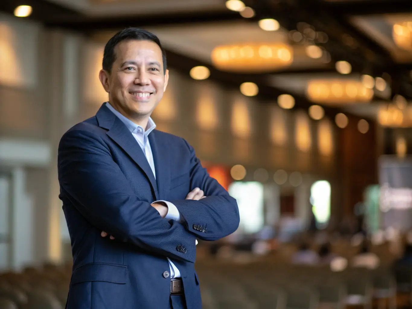 A professional headshot of a keynote speaker at the airbushub.uno conference, set against a backdrop of the conference venue. The speaker is smiling confidently, and the image is well-lit and high-resolution, conveying expertise and approachability.